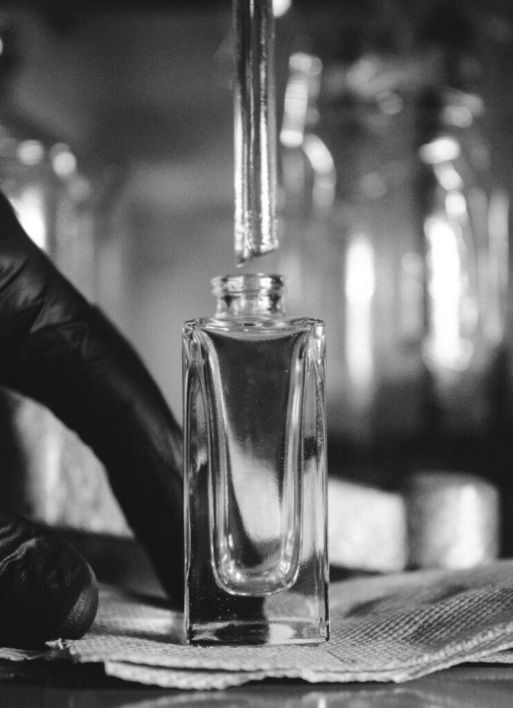 Perfumer measuring fragrance oil concentration into a glass bottle