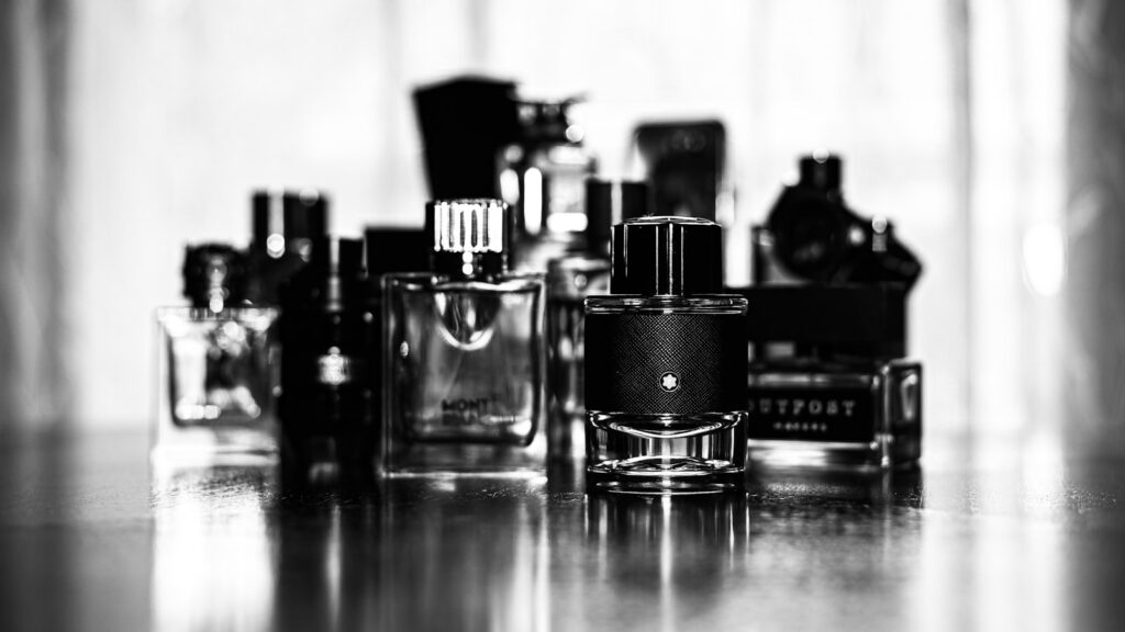Grayscale editorial photo of perfume bottles, representing fragrance longevity and how scent lasts through the day