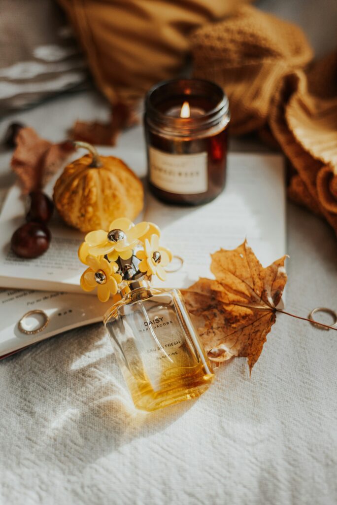 Perfume bottle with dried autumn leaves, seasonal fragrance styling